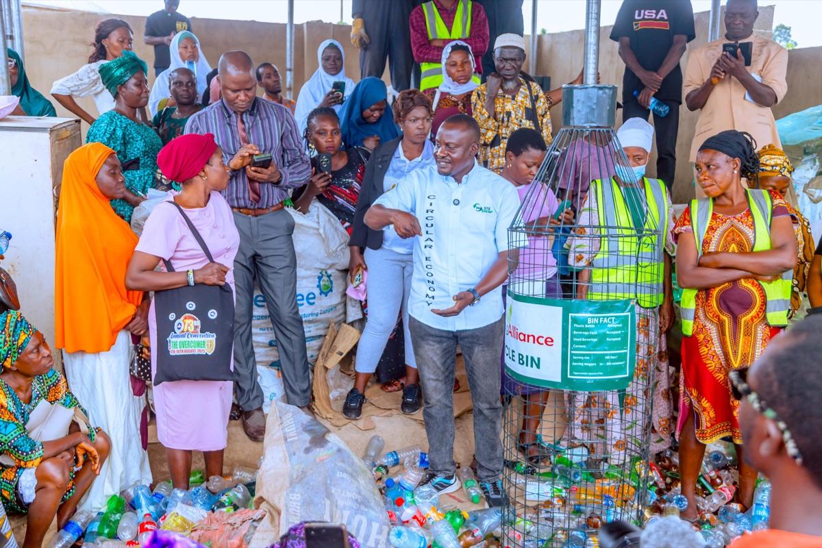 Community members gathered around a recycling bin demonstration at a waste management awareness event in Osun State