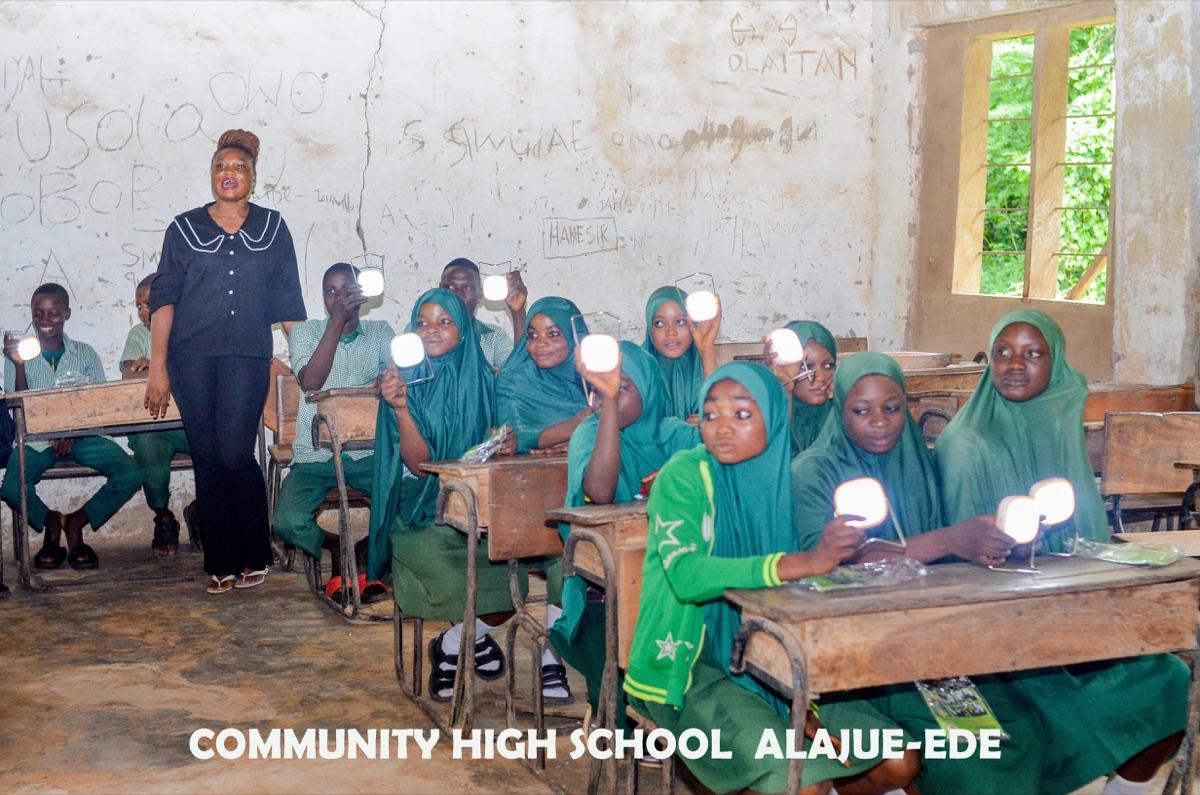 Students at Community High School Alajue-Ede holding up lit solar lanterns received through the Imole One Child One Lantern campaign in Osun State