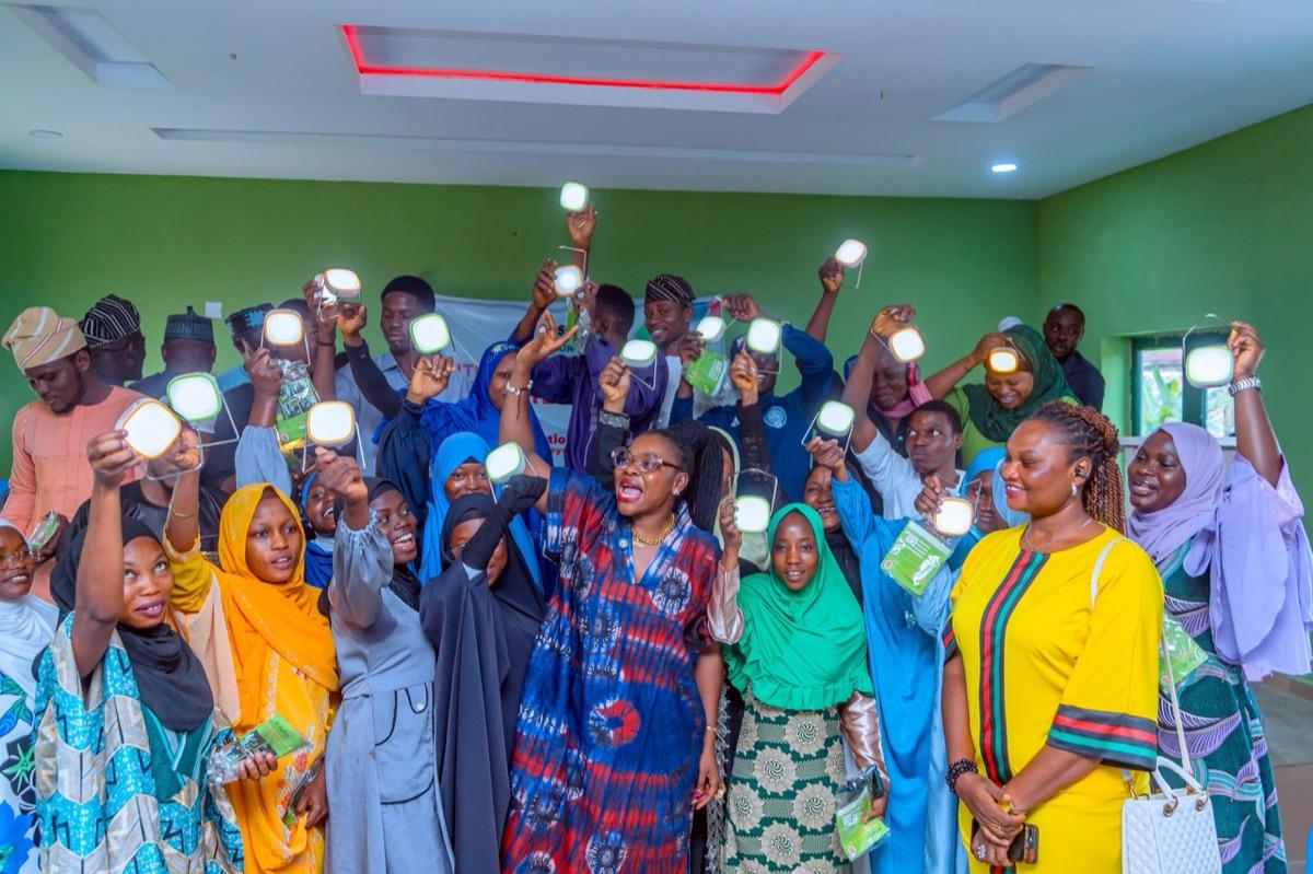 Community youth group in Osun State celebrating with lit solar lanterns raised high, marking the success of the Imole Solar Lantern distribution programme